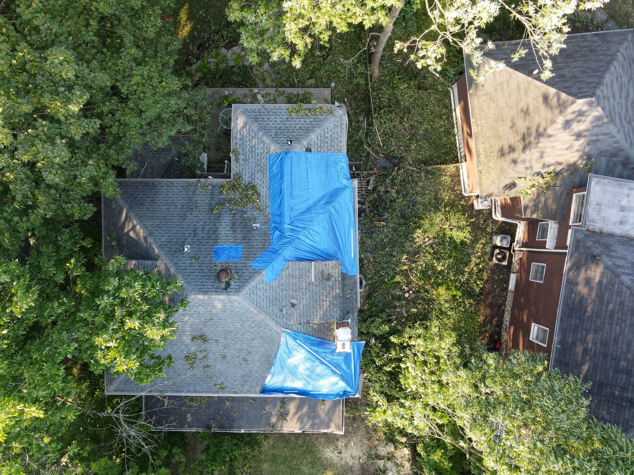 Bravo Roofing truck, dump trailer and crew on site at a house