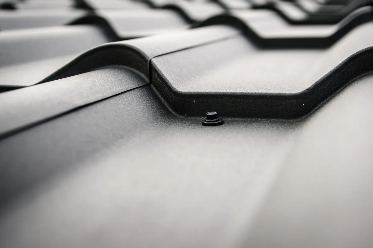 Close-up of a black steel roof with visible rivets and tiles, highlighting roofing materials for emergency repairs.
