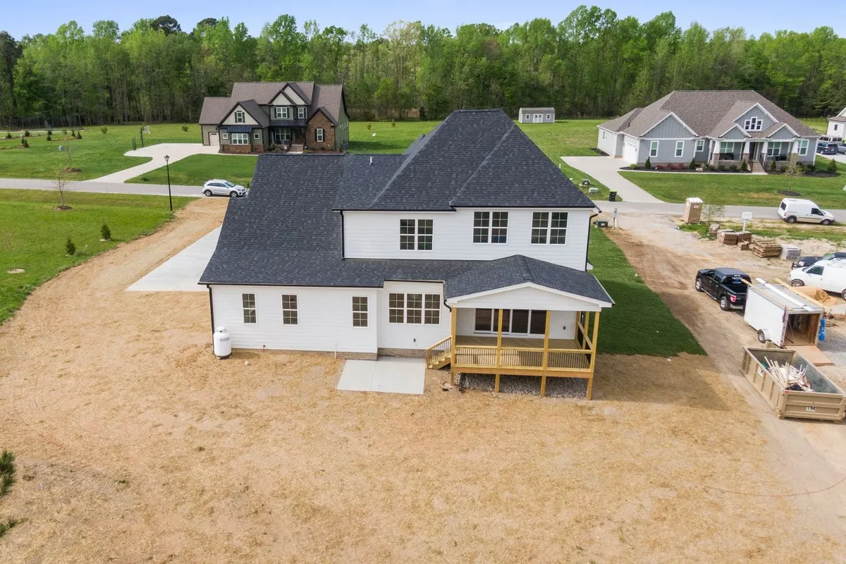 Aerial view of a suburban home under construction surrounded by greenery, highlighting roofing considerations.