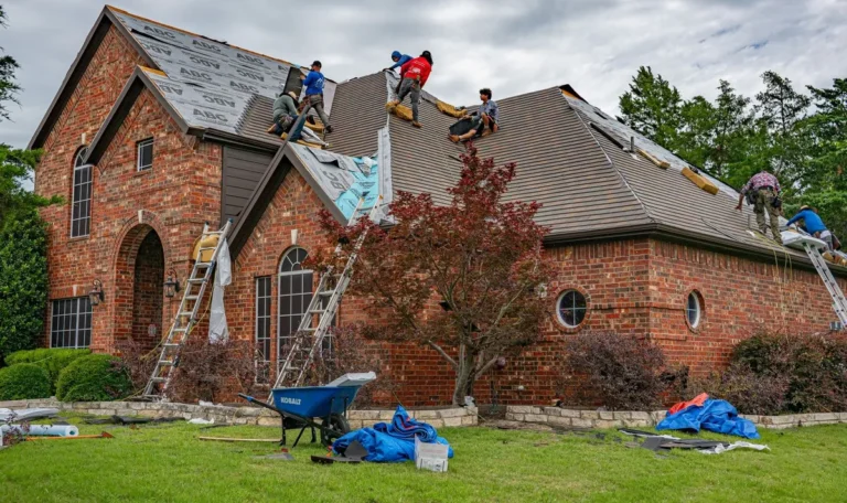 Roofers installing shingles on a brick home, highlighting the importance of choosing the right roofing company.