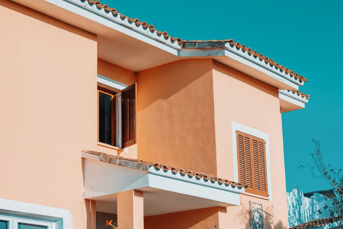 Mediterranean style house with orange hues under a bright blue sky, illustrating ideal roof conditions.