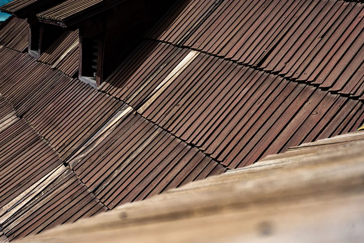 Close-up of aged wooden roof shingles highlighting their texture and architectural style related to roof maintenance.